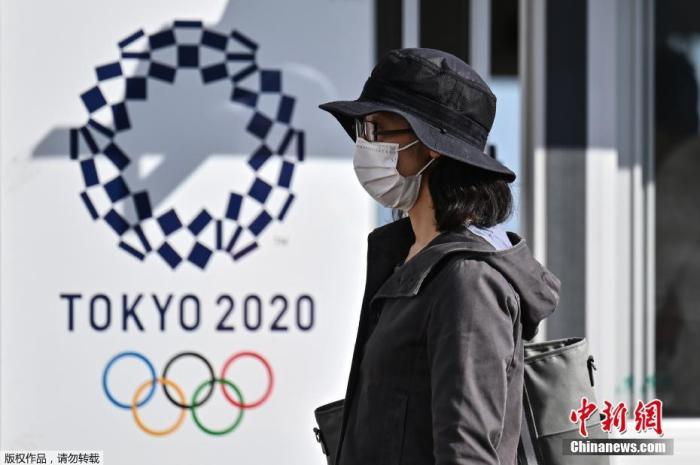 资料图：当地时间10月21日，东京奥运会和残奥会组织委员会21日在东京向媒体公开了，观众等进入赛场时通过的行李安检区运营的实证试验。奥组委将根据本次的测试结果等，讨论奥运时的对策。图为一名女士走过2020年东京奥运会海报。