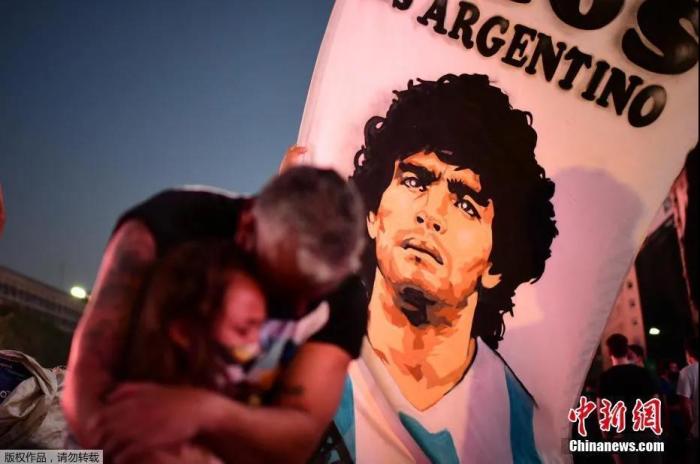 当地时间11月25日，阿根廷首都布宜诺斯艾利斯，一名男子搂着他的女儿悼念足球传奇人物迭戈·马拉多纳。
