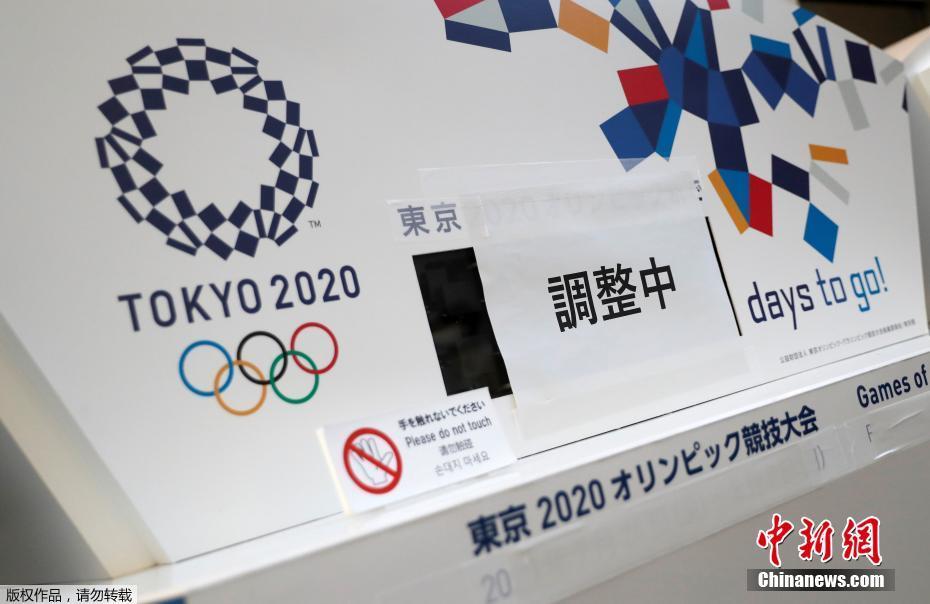 资料图：2020年3月25日，在日本东京中央区，一间写字楼内的原本显示东京奥运会倒计时的电子屏被贴上了“正在调整”，下方奥运会的原定举办日期也被遮挡了起来。