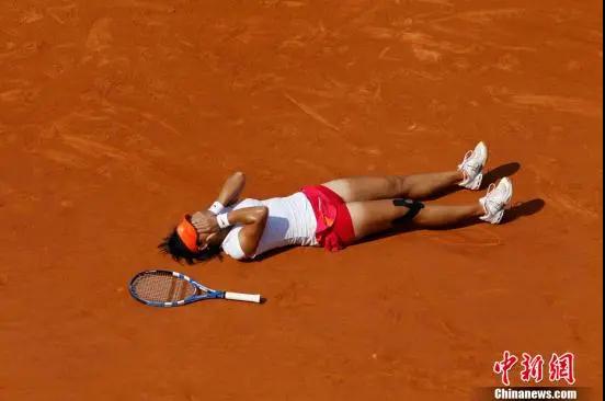 资料图：李娜2011年法网决赛取胜后，掩面躺在比赛场地上。