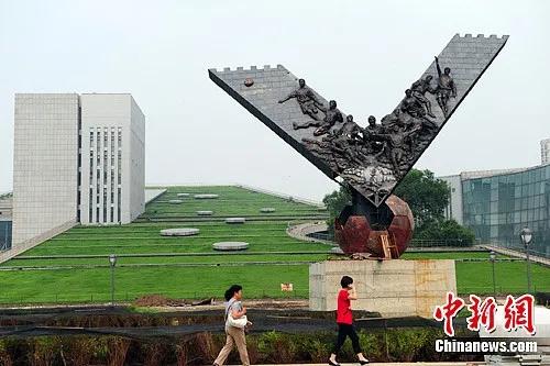 2012年，中国男足冲击2002年韩日世界杯纪念铜塑时隔5年再现辽宁省沈阳市。图为当地市民从雕塑前经过。/p中新社发 于海洋 摄
