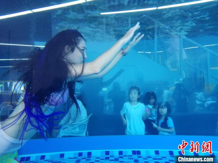 景区“美人鱼”表演吸引游客驻足观看。(资料图) 记者王晓斌 摄