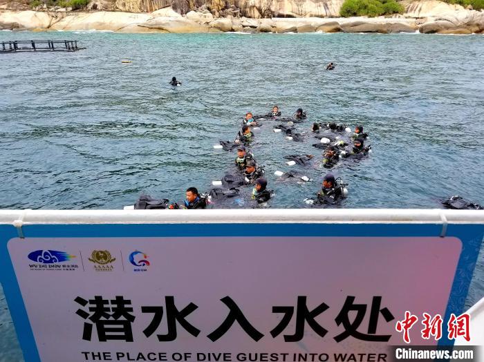 三亚蜈支洲岛，潜水教练浮在海面，等待体验潜水的游客。　记者王晓斌 摄