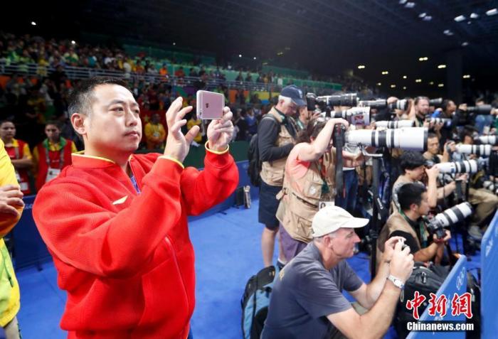 里约奥运会乒乓球男子单打决赛，马龙战胜卫冕冠军张继科夺得冠军，成为世界上第五个实现大满贯的男子选手。图为刘国梁用手机记录精彩瞬间。/p中新网记者 杜洋 摄