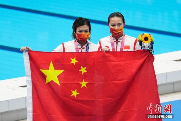东京奥运会女子单人3米板跳水颁奖仪式，中国队包揽金银牌。图为金牌得主施廷懋(左)与王涵(右)手持国旗合影。/p中新社记者 杜洋 摄